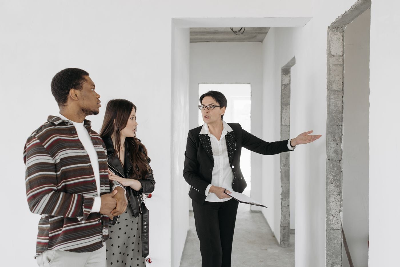 Real estate agent shows a house to a couple, discussing features.
